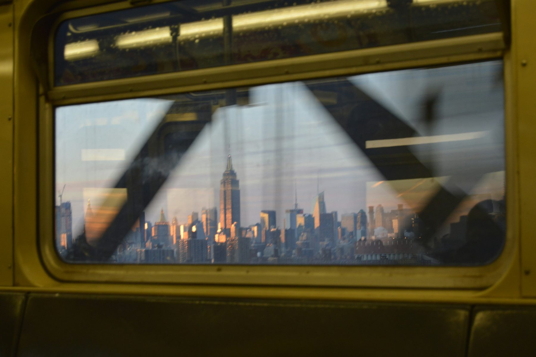 View of the Manhattan skyline at sunset through a train window