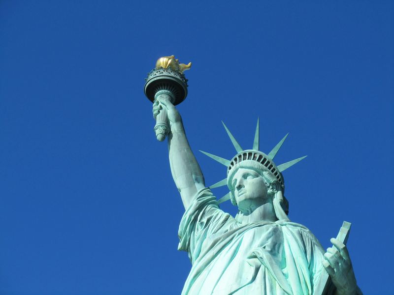 The Statue of Liberty's torch and crown against a blue sky